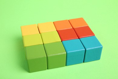 Photo of Many wooden colorful cubes on green background