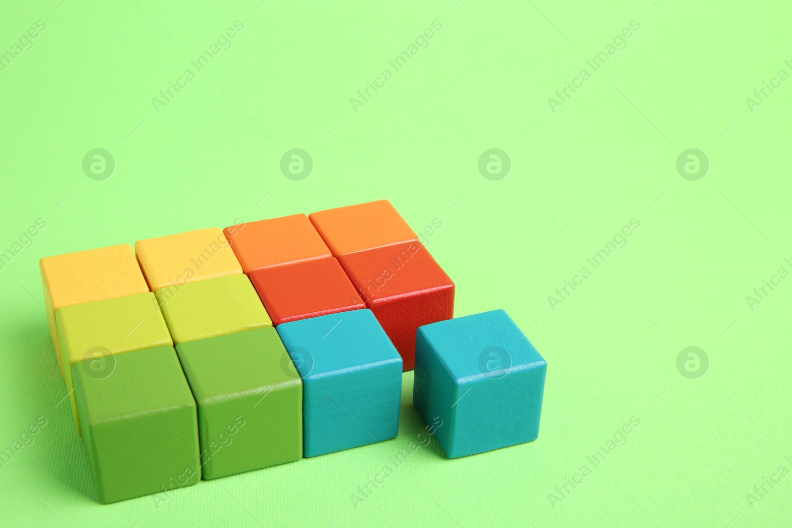 Photo of Many wooden colorful cubes on green background, space for text