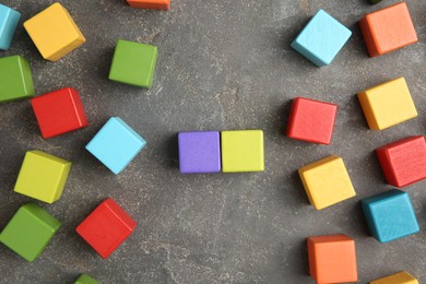 Photo of Many wooden colorful cubes on gray textured background, top view