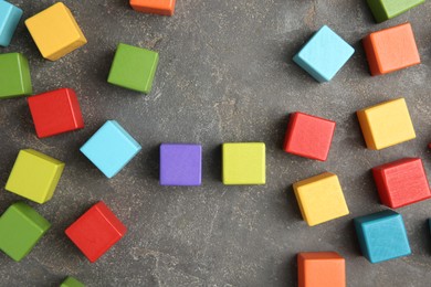 Photo of Many wooden colorful cubes on gray textured background, top view