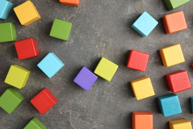 Photo of Many wooden colorful cubes on gray textured background, top view