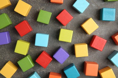 Photo of Many wooden colorful cubes on gray textured background, top view