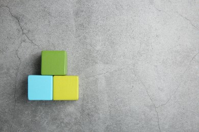 Photo of Pyramid of colorful cubes on gray textured background, top view. Space for text