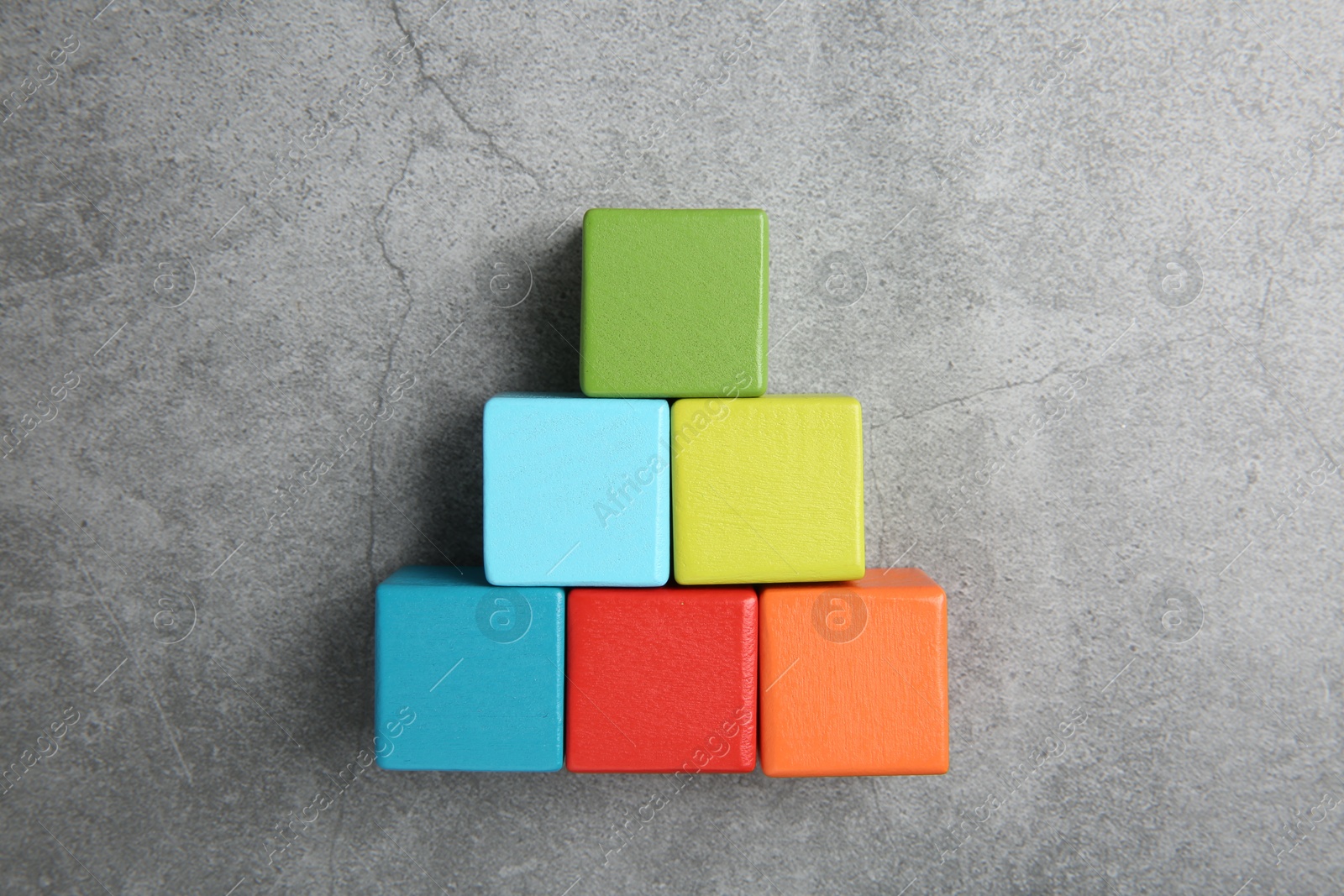 Photo of Pyramid of colorful cubes on gray textured background, top view