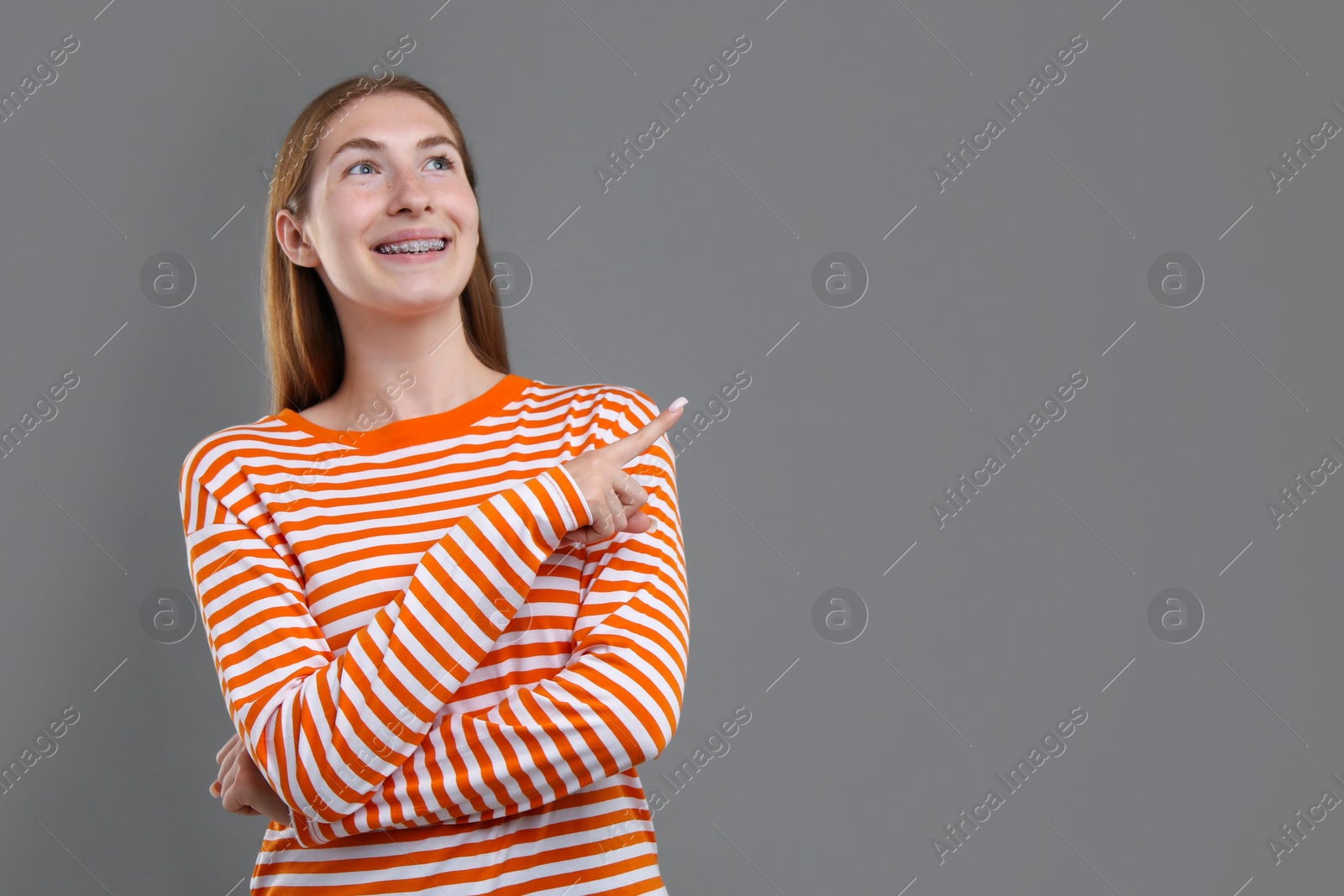 Photo of Smiling girl with braces on grey background, space for text