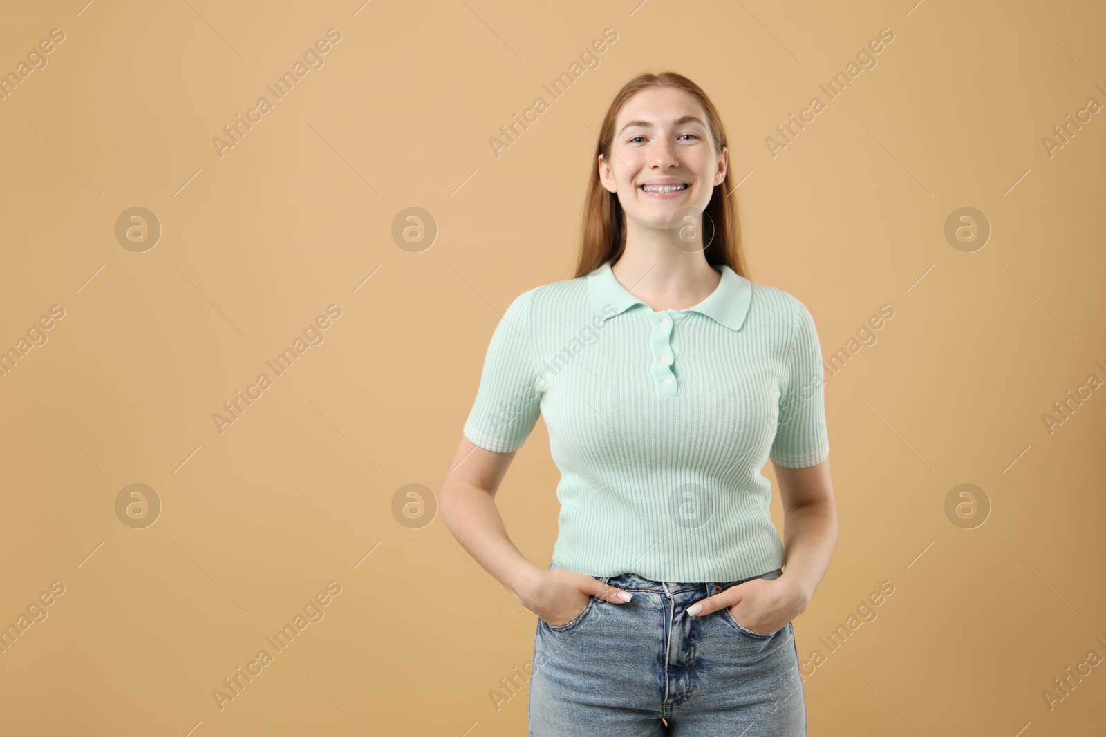 Photo of Smiling girl with braces on beige background, space for text