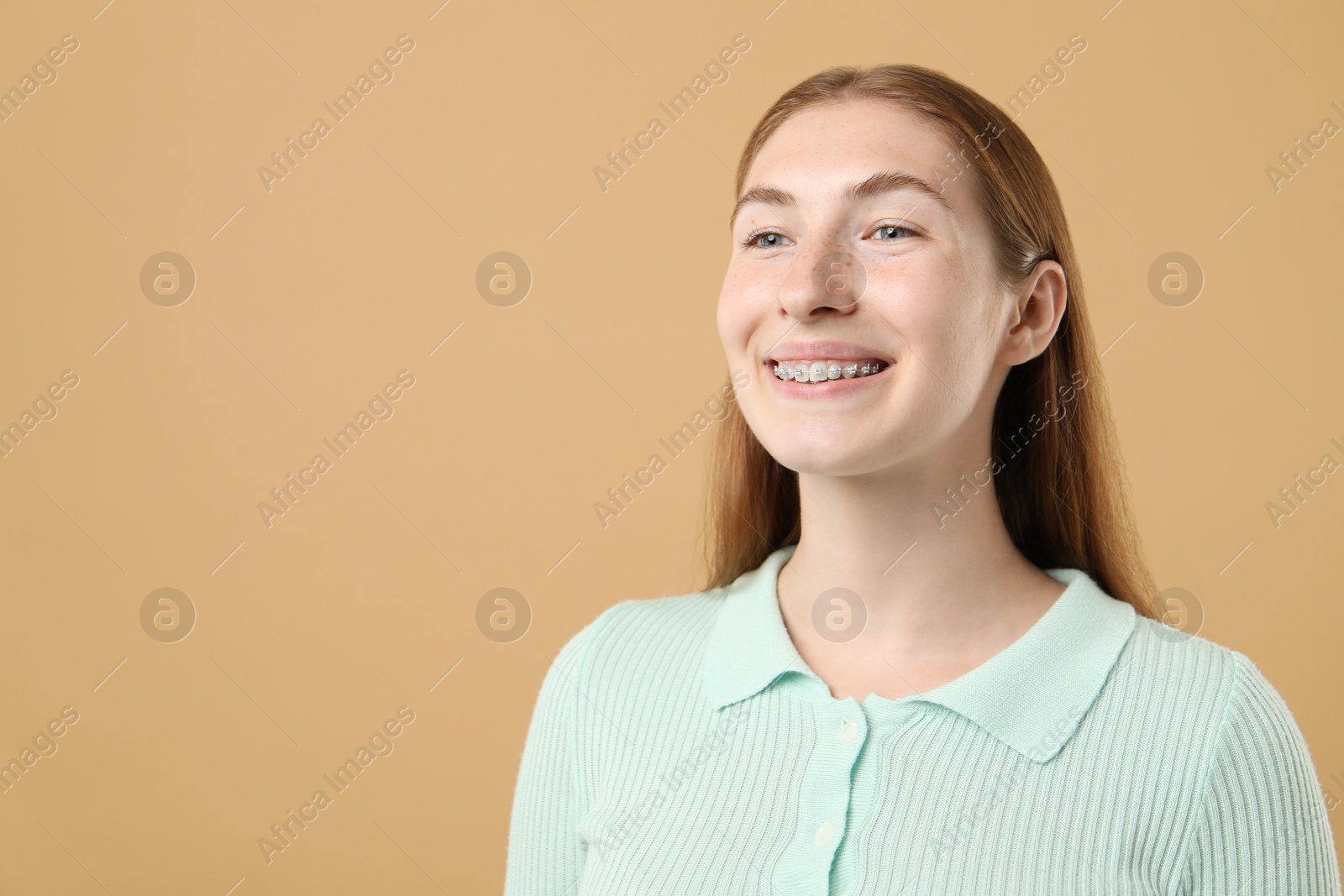 Photo of Smiling girl with braces on beige background, space for text