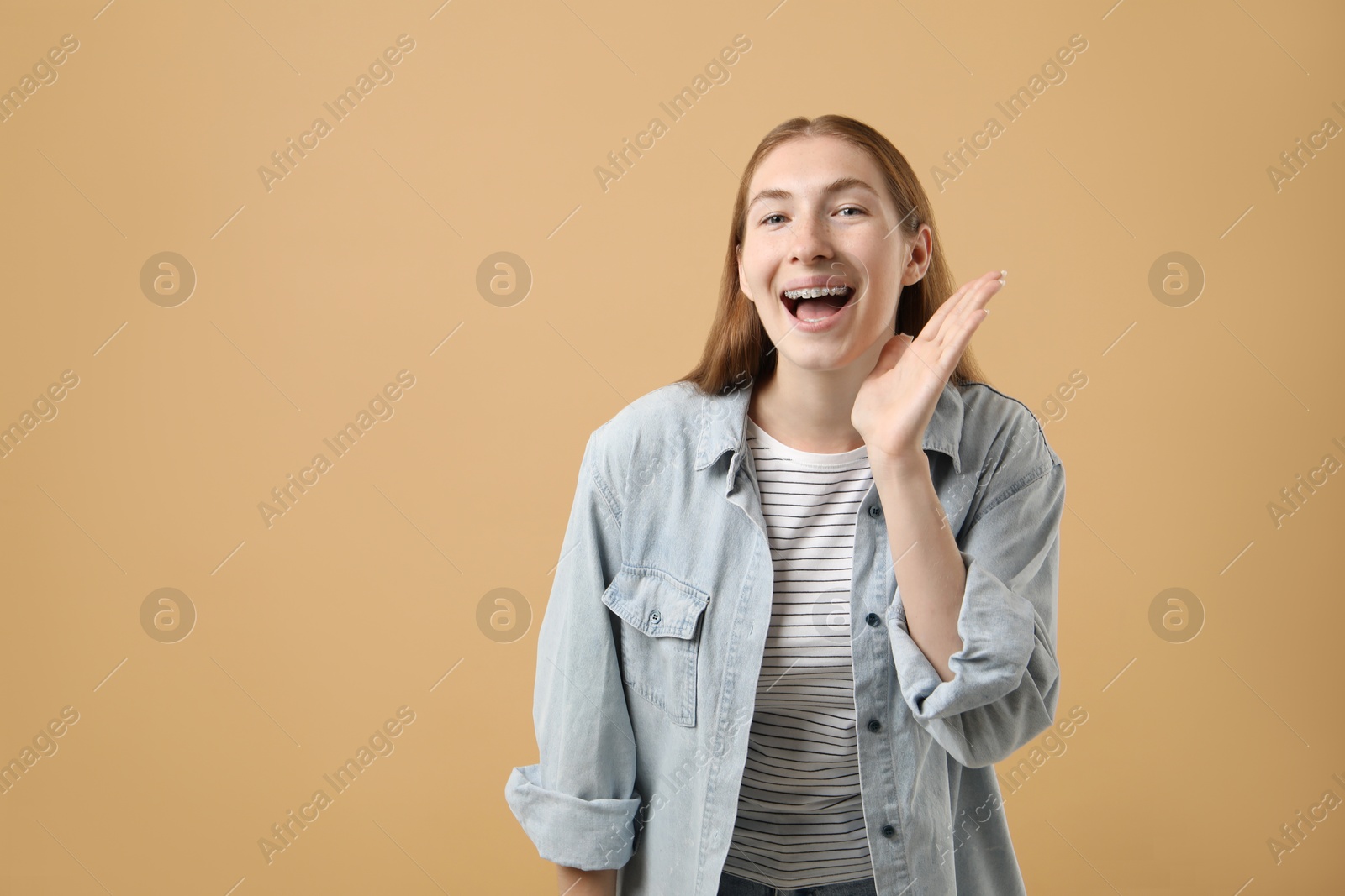 Photo of Smiling girl with braces on beige background, space for text