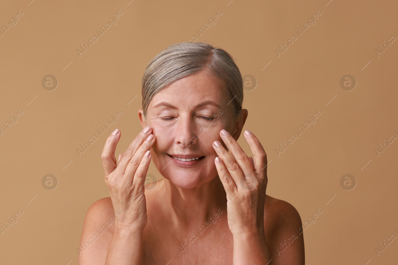 Photo of Beautiful woman doing facial massage on beige background