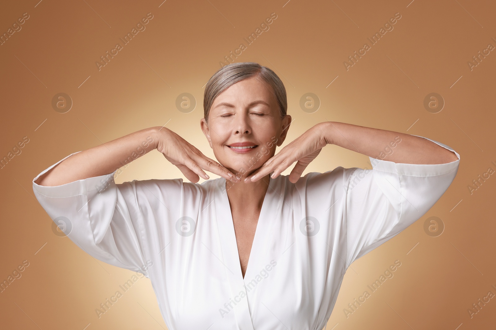 Photo of Face massage. Beautiful woman with healthy skin on beige background