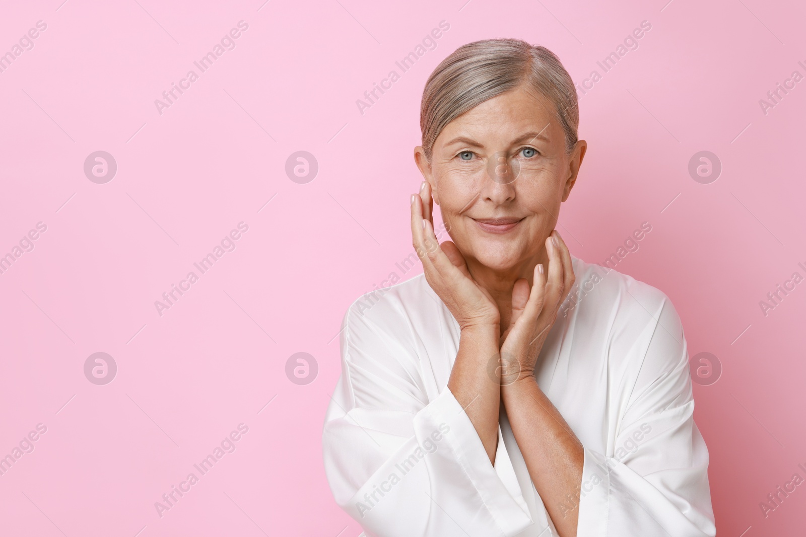 Photo of Face massage. Beautiful woman with healthy skin on pink background, space for text