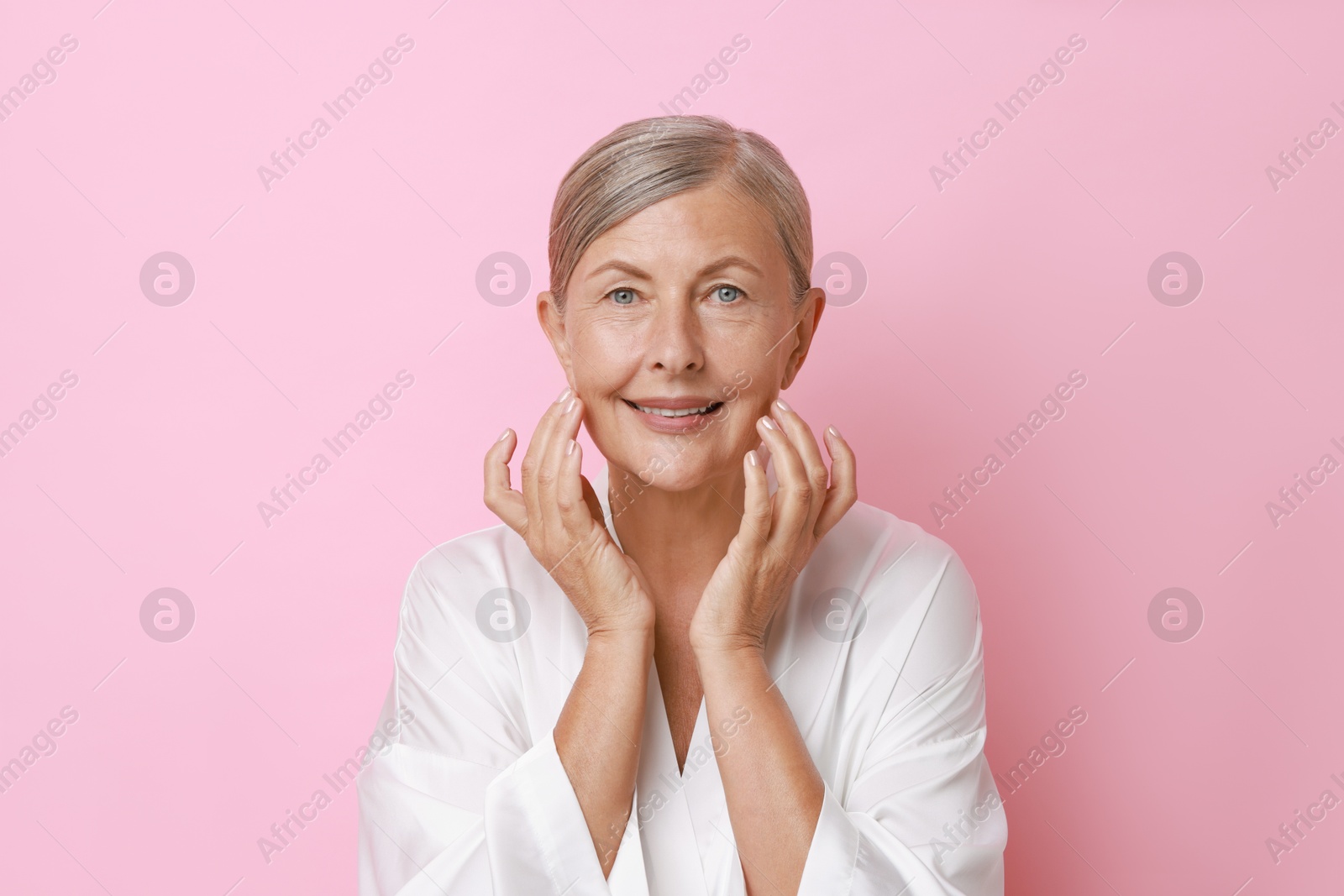 Photo of Face massage. Beautiful woman with healthy skin on pink background