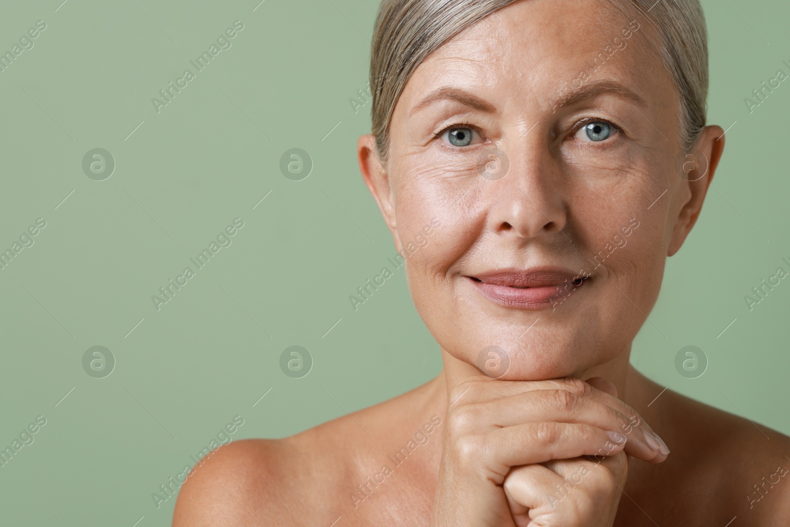 Photo of Face massage. Beautiful woman with healthy skin on light green background, closeup