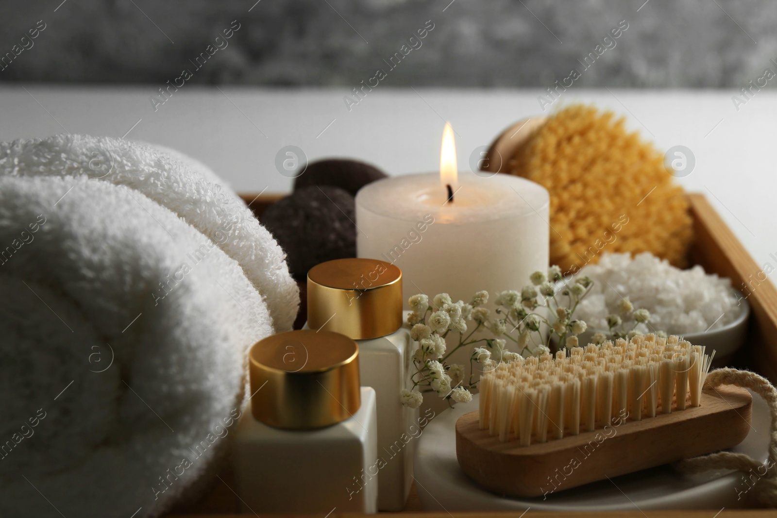 Photo of Burning candle and other spa supplies on table, closeup