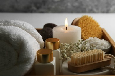 Photo of Burning candle and other spa supplies on table, closeup