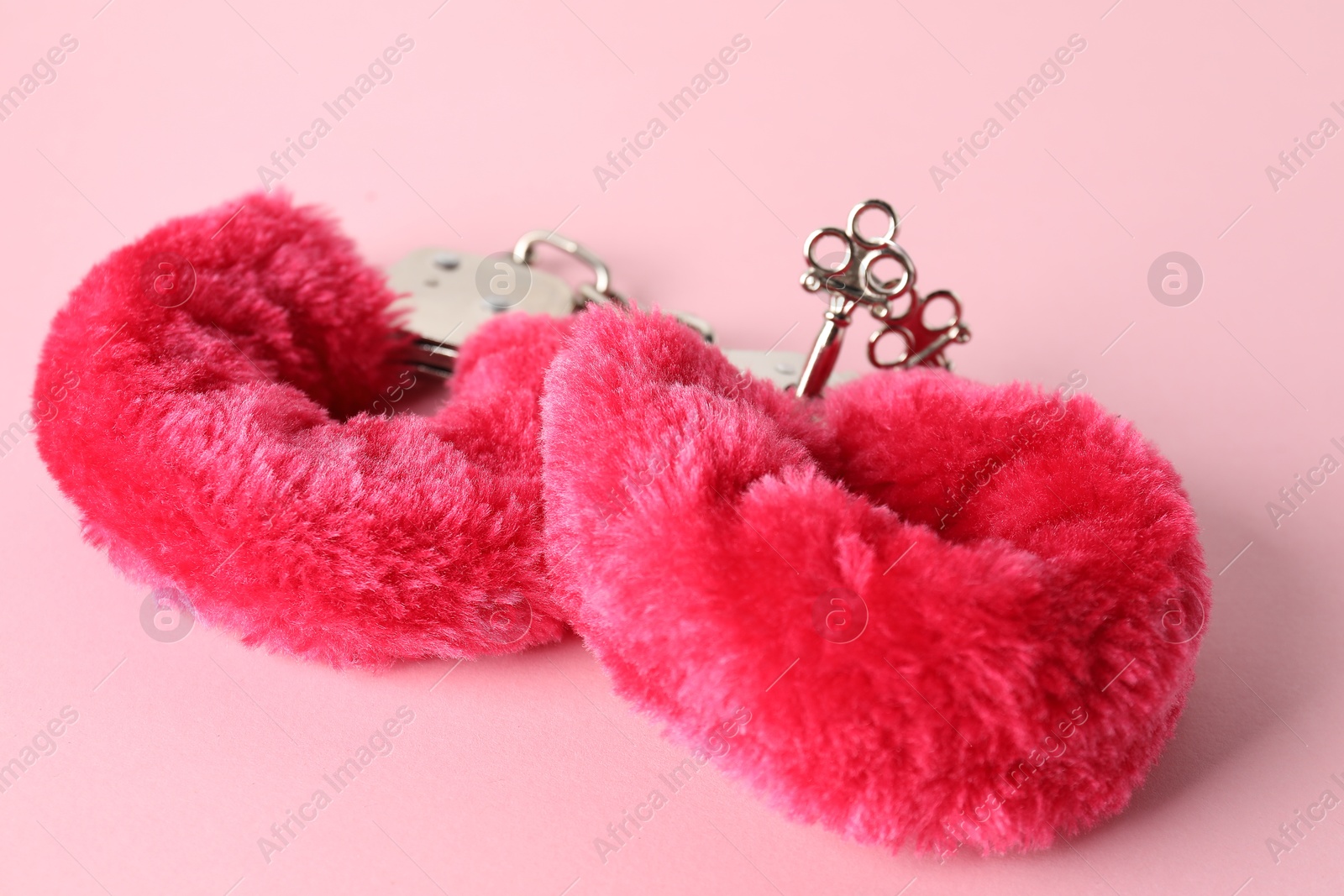 Photo of Fluffy handcuffs on pink background, closeup. Sex toy