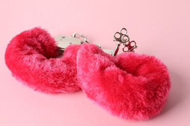 Photo of Fluffy handcuffs on pink background, closeup. Sex toy