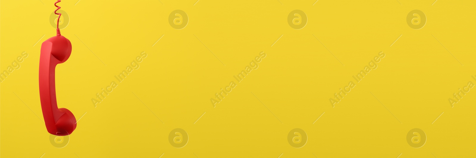 Image of Red corded telephone handset on yellow background. Banner design with space for text