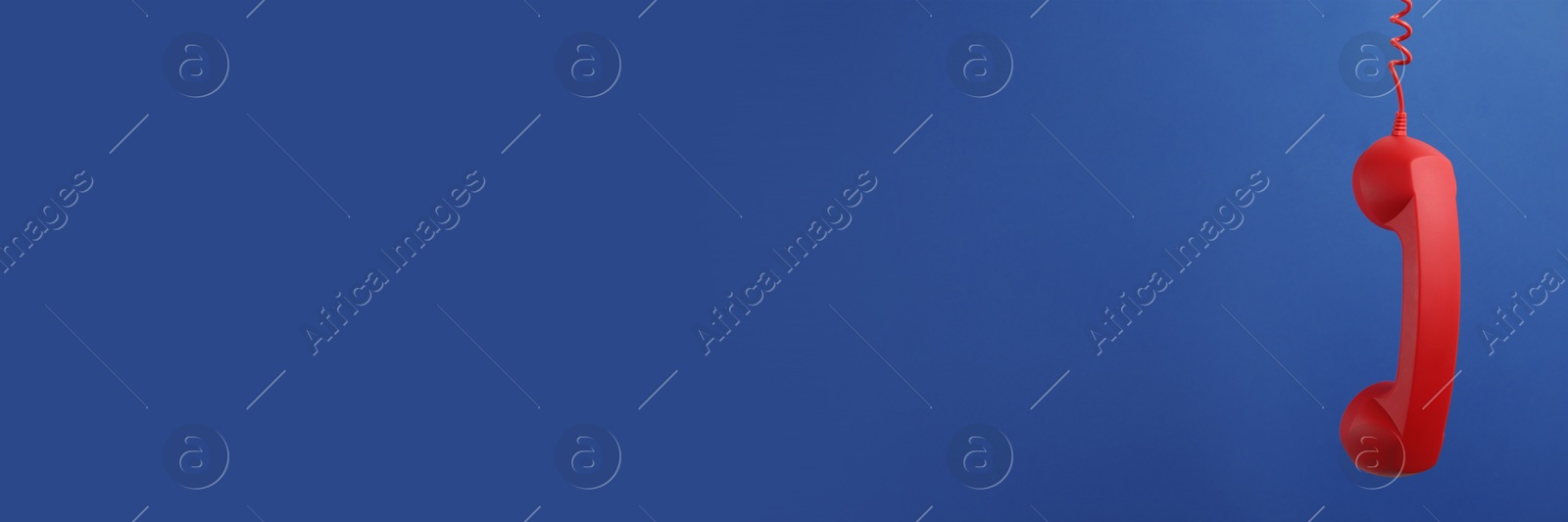 Image of Red corded telephone handset on blue background. Banner design with space for text