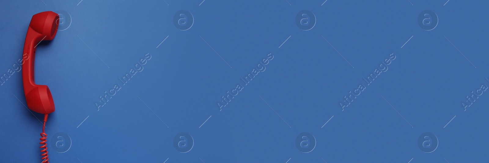 Image of Red corded telephone handset on blue background, top view. Banner design with space for text