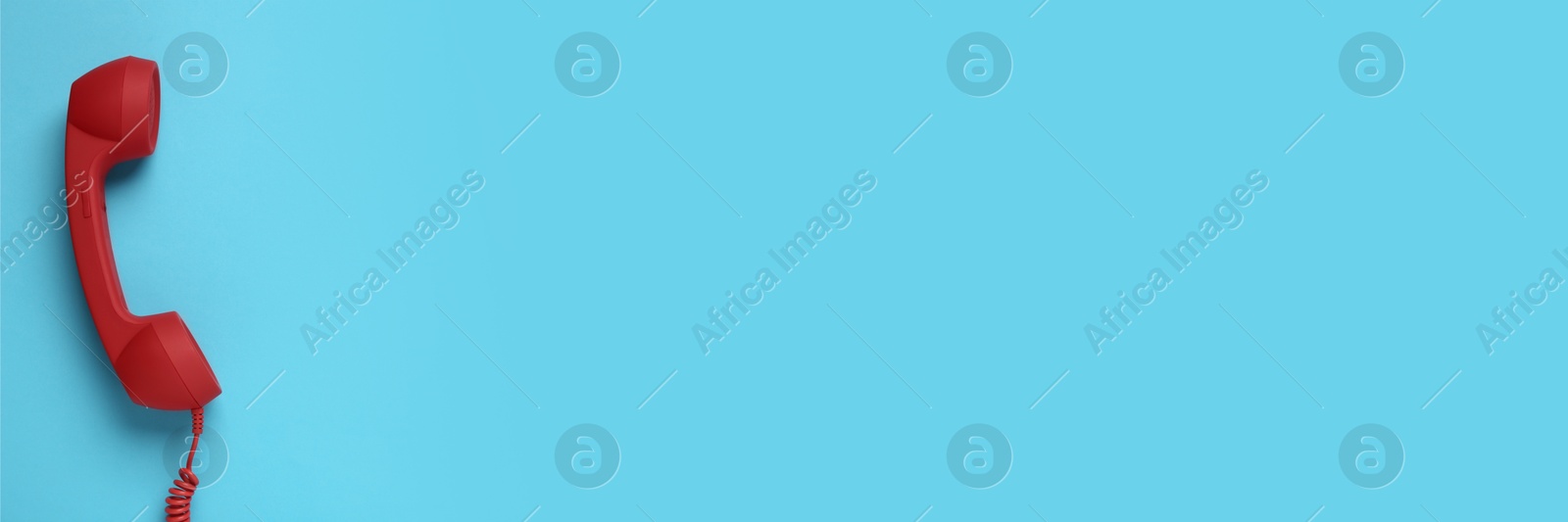 Image of Red corded telephone handset on light blue background, top view. Banner design with space for text