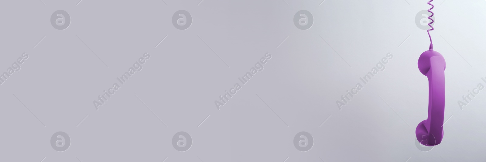 Image of Purple corded telephone handset on grey background. Banner design with space for text