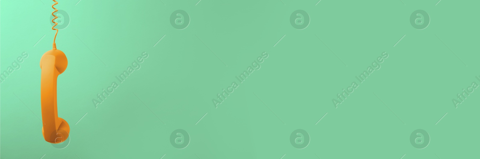 Image of Orange corded telephone handset on aquamarine color background. Banner design with space for text