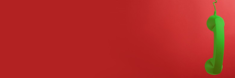 Image of Green corded telephone handset on red background. Banner design with space for text