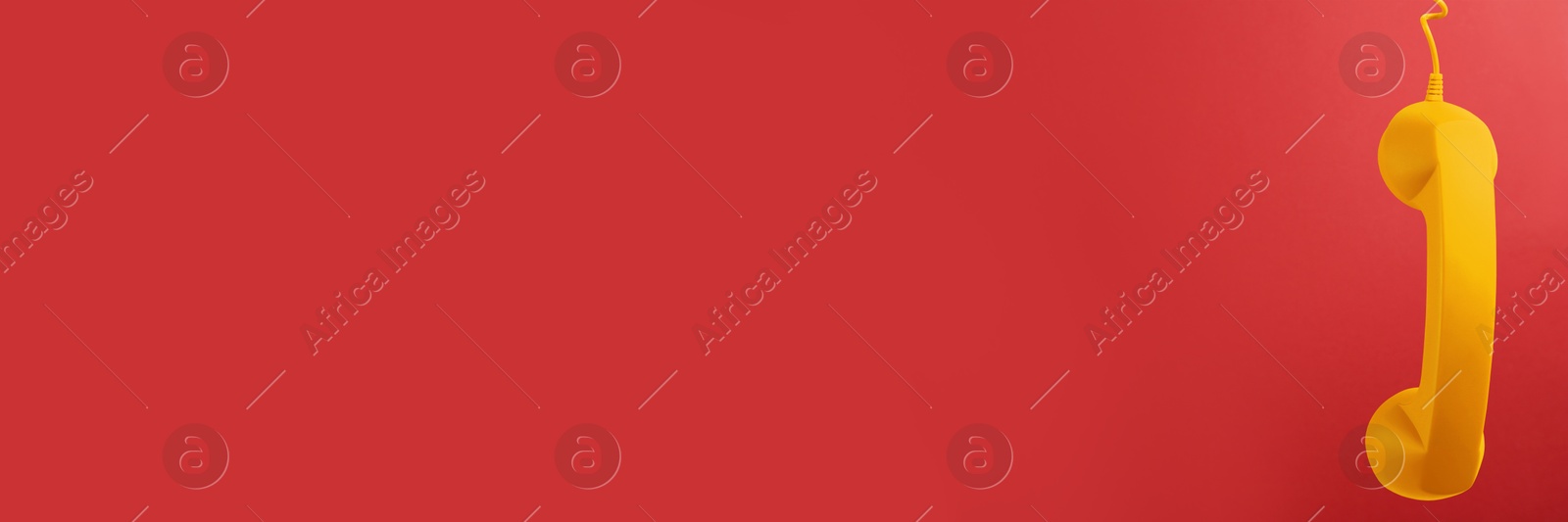 Image of Yellow corded telephone handset on red background. Banner design with space for text