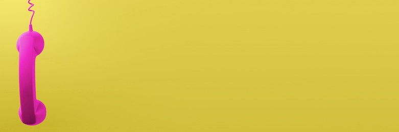 Image of Magenta color telephone handset on yellow background. Banner design with space for text