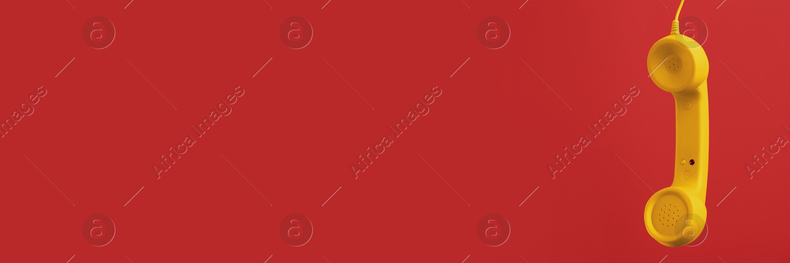 Image of Yellow corded telephone handset on red background. Banner design with space for text