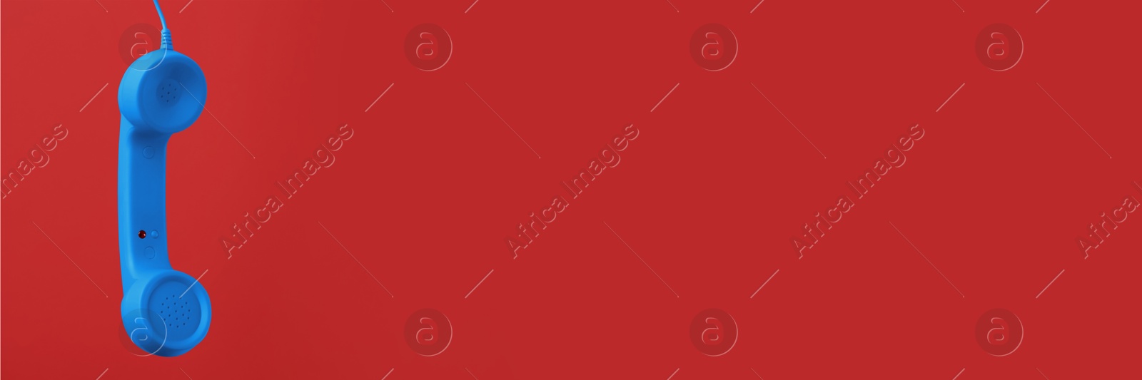 Image of Light blue corded telephone handset on red background. Banner design with space for text