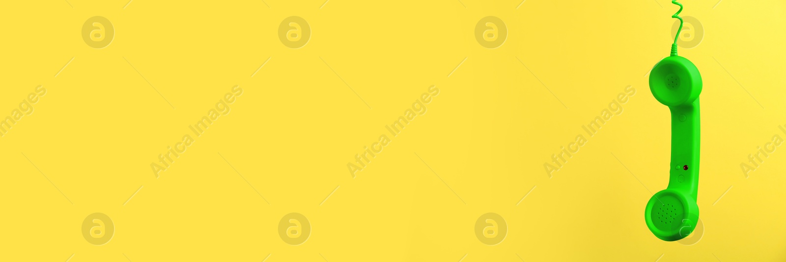 Image of Green corded telephone handset on yellow background. Banner design with space for text