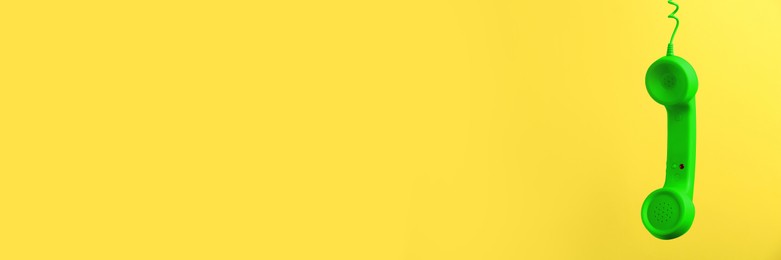 Image of Green corded telephone handset on yellow background. Banner design with space for text