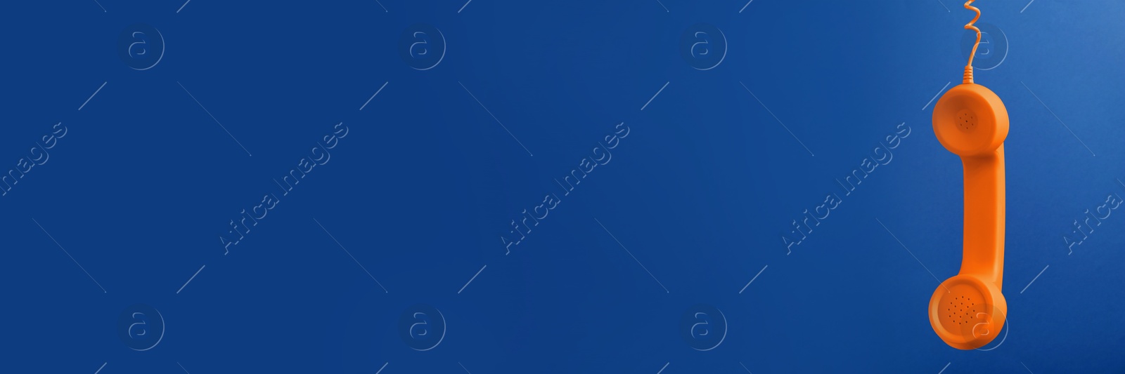 Image of Orange corded telephone handset on blue background. Banner design with space for text