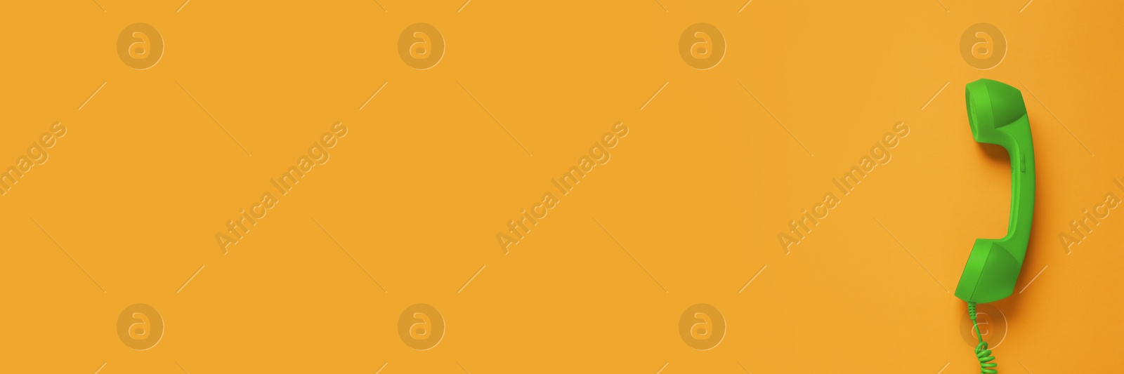 Image of Green corded telephone handset on orange background, top view. Banner design with space for text