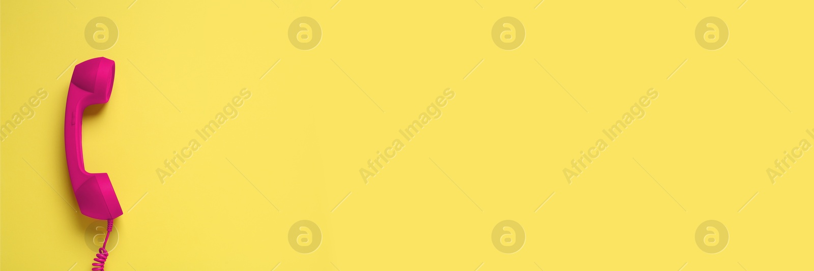 Image of Magenta color telephone handset on yellow background, top view. Banner design with space for text