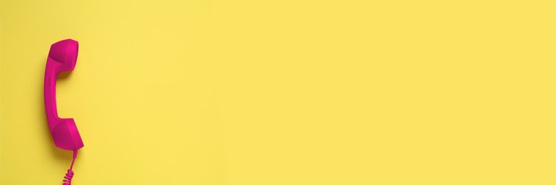 Image of Magenta color telephone handset on yellow background, top view. Banner design with space for text