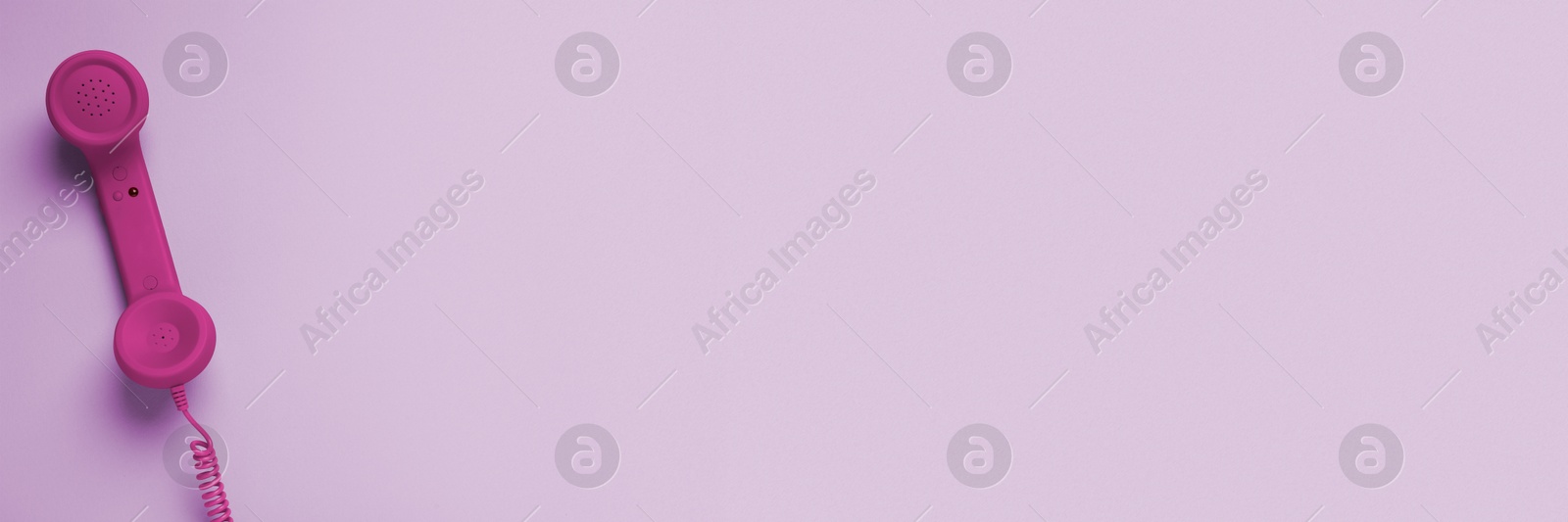 Image of Magenta color telephone handset on violet background, top view. Banner design with space for text