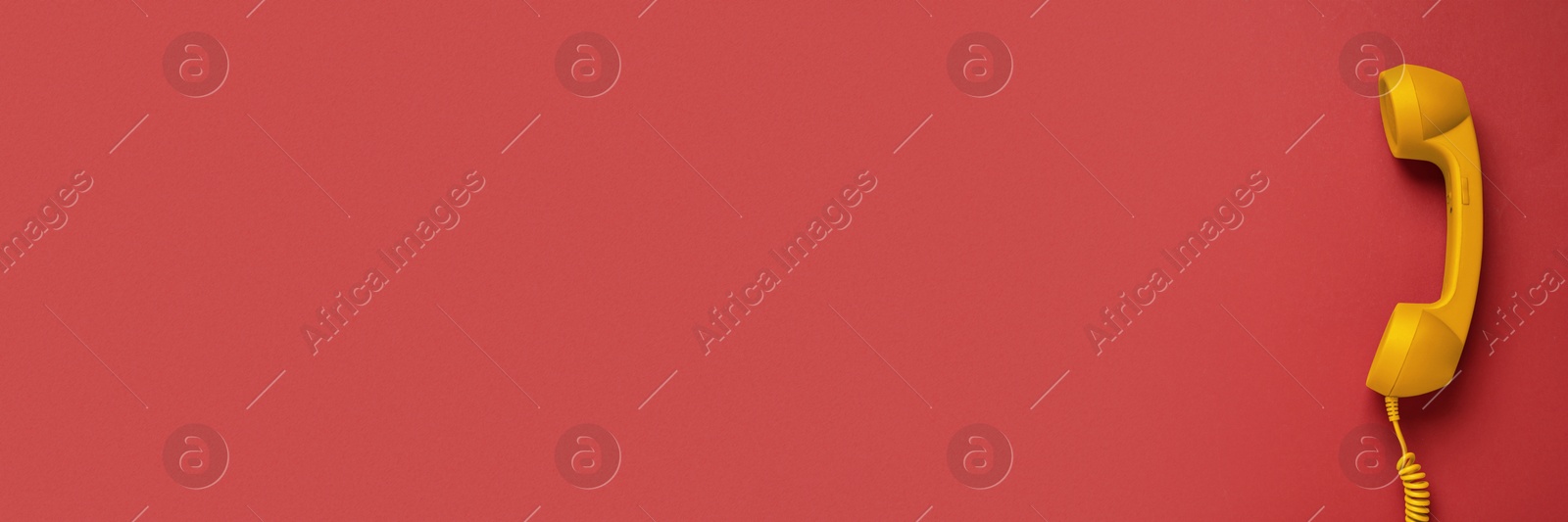 Image of Yellow corded telephone handset on red background, top view. Banner design with space for text