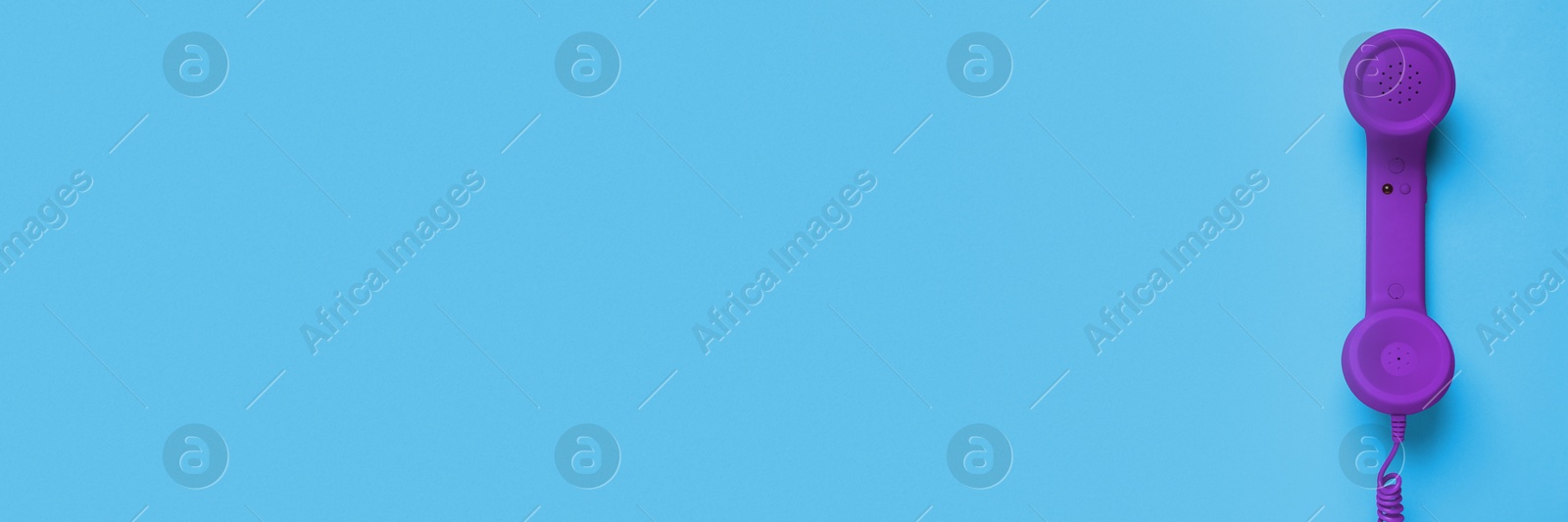 Image of Purple corded telephone handset on light blue background, top view. Banner design with space for text