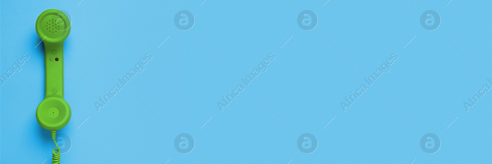 Image of Green corded telephone handset on light blue background, top view. Banner design with space for text