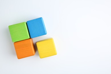 Photo of Many wooden colorful cubes on white background, top view. Space for text