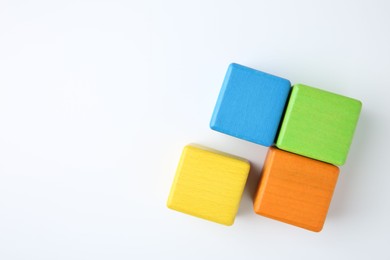 Photo of Many wooden colorful cubes on white background, top view. Space for text