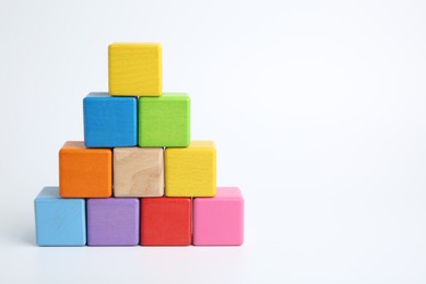 Photo of Pyramid of colorful cubes on white background, space for text