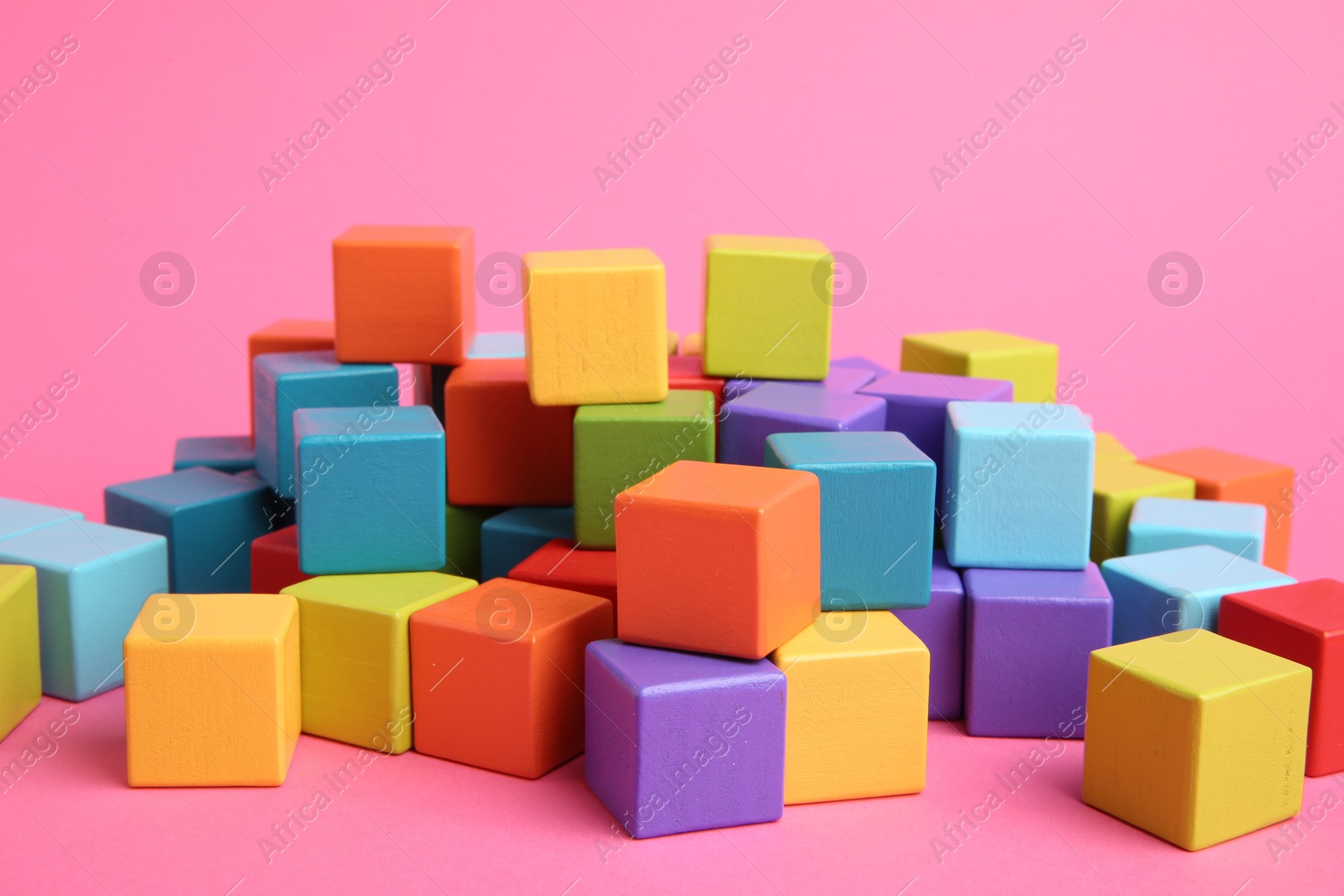 Photo of Many wooden colorful cubes on pink background