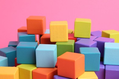 Photo of Many wooden colorful cubes on pink background, closeup