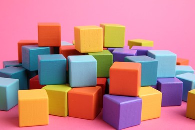 Photo of Many wooden colorful cubes on pink background, closeup