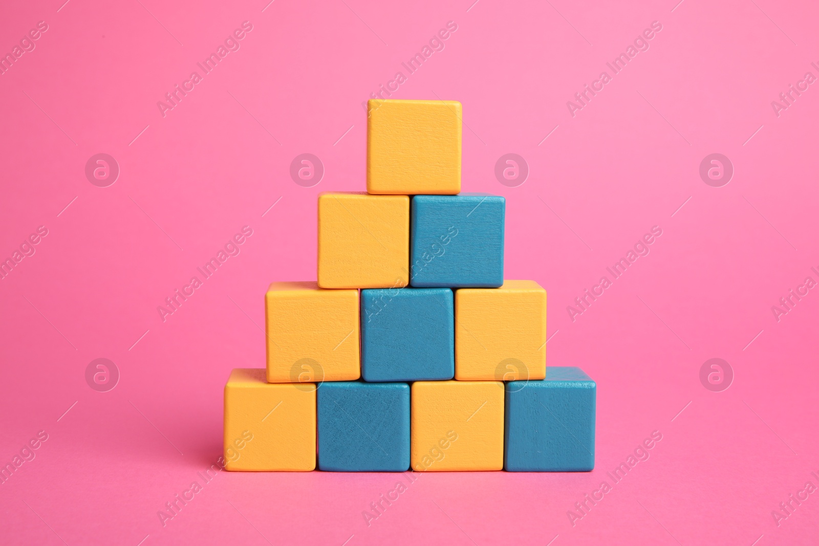 Photo of Pyramid of colorful cubes on pink background