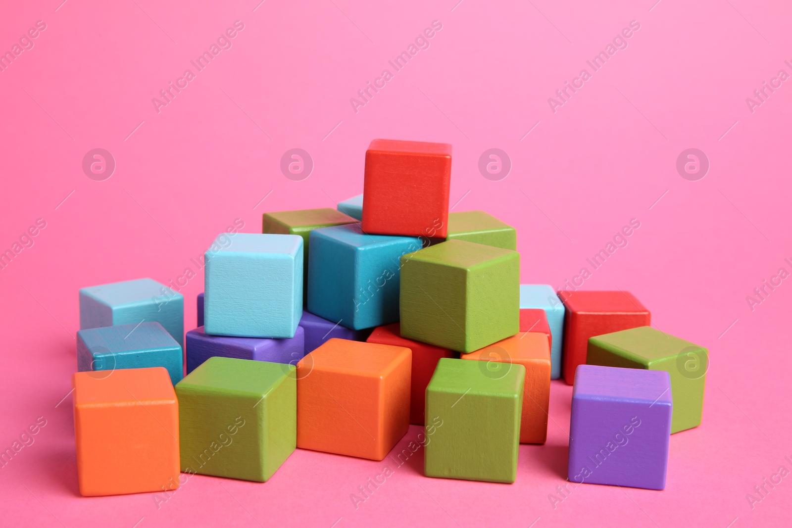 Photo of Many wooden colorful cubes on pink background